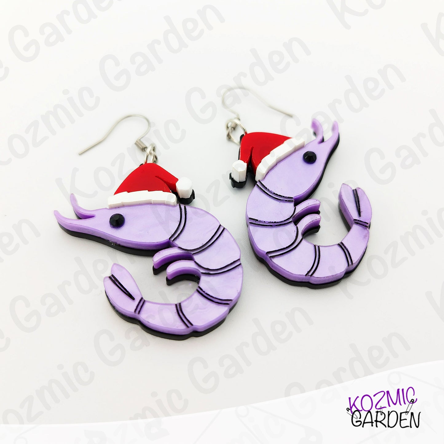 Purple shrimp earrings with Santa hats on a white background with 'Kozmic Garden' branding.