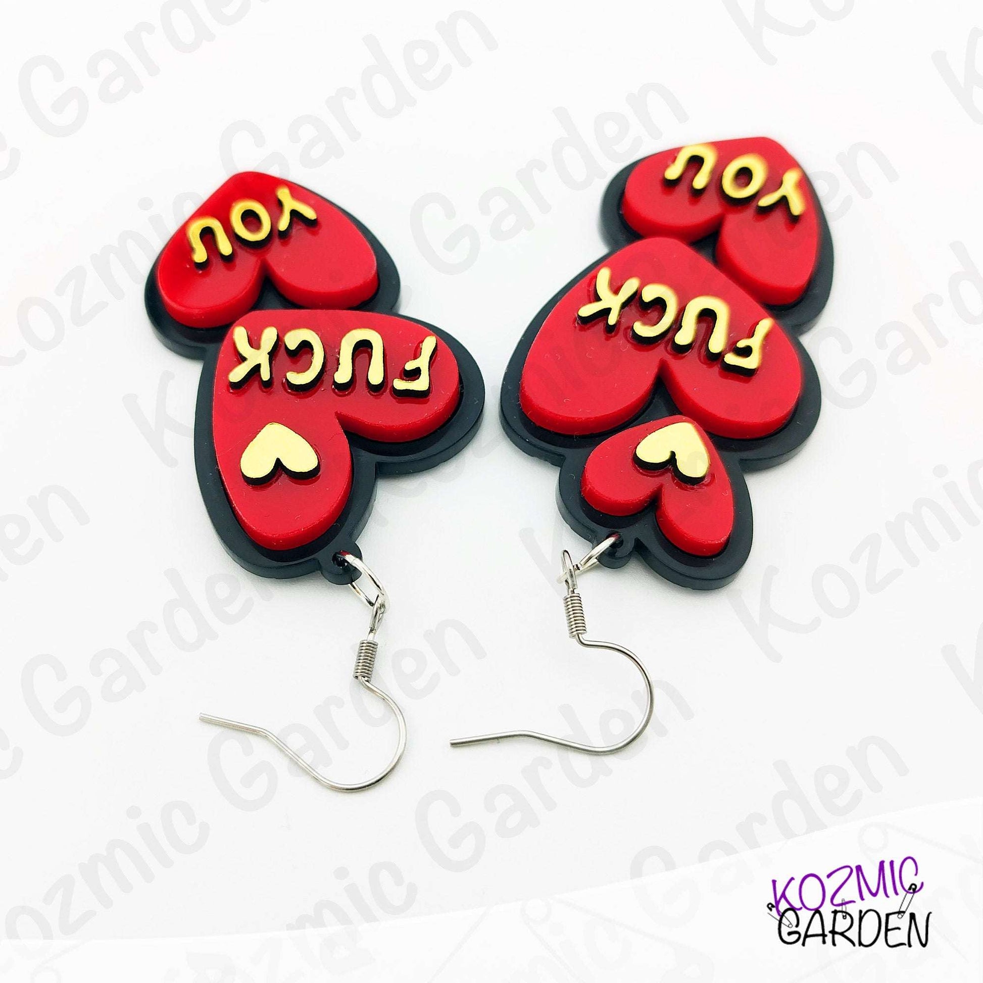 Red heart-shaped earrings with yellow text on a white background, branded 'Kozmic Garden'.