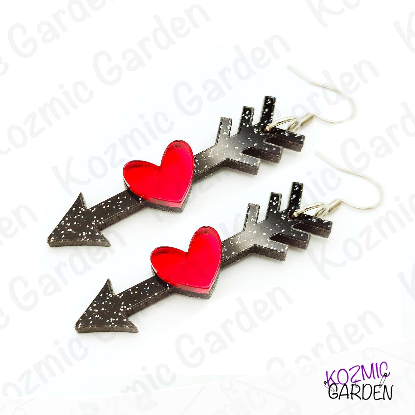Heart-shaped earrings with black arrows on a white background, branded 'Kozmic Garden'.
