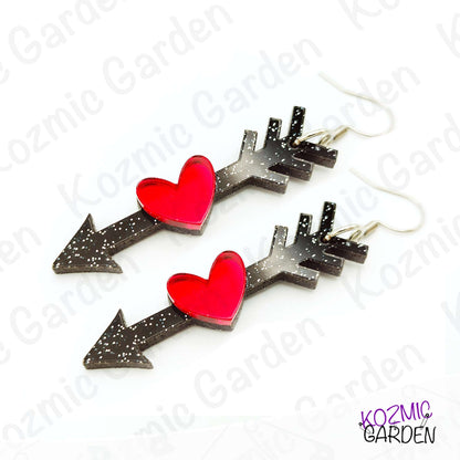 Heart-shaped earrings with black arrows on a white background, branded 'Kozmic Garden'.