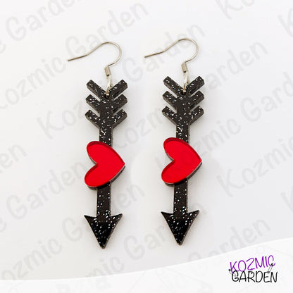Black arrow-shaped earrings with red heart details on a white background, branded 'Kozmic Garden'.