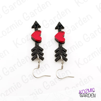 Black arrow-shaped earrings with red heart centers on a white background, branded 'Kozmic Garden'.