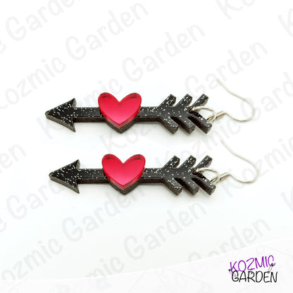 Pair of arrow-shaped earrings with red hearts on a white background, branded 'Kozmic Garden'.