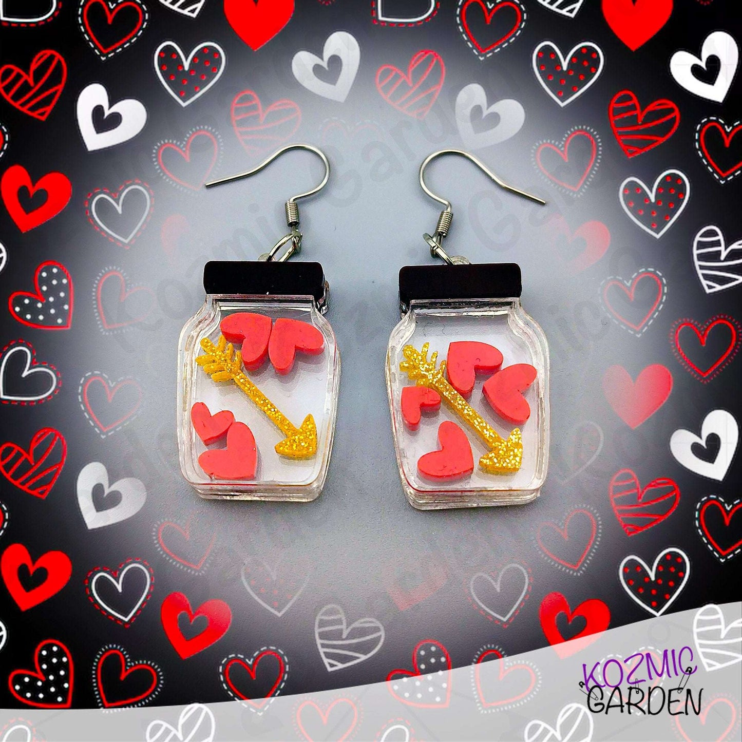Jar-shaped earrings with hearts and arrow design on a heart-patterned background, branded 'Kozmic Garden'.