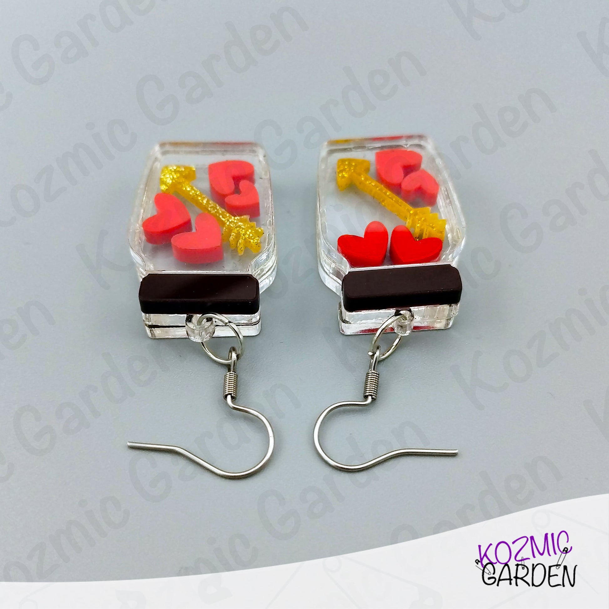 Pair of earrings with heart and key design on a gray background, branded 'Kozmic Garden'.