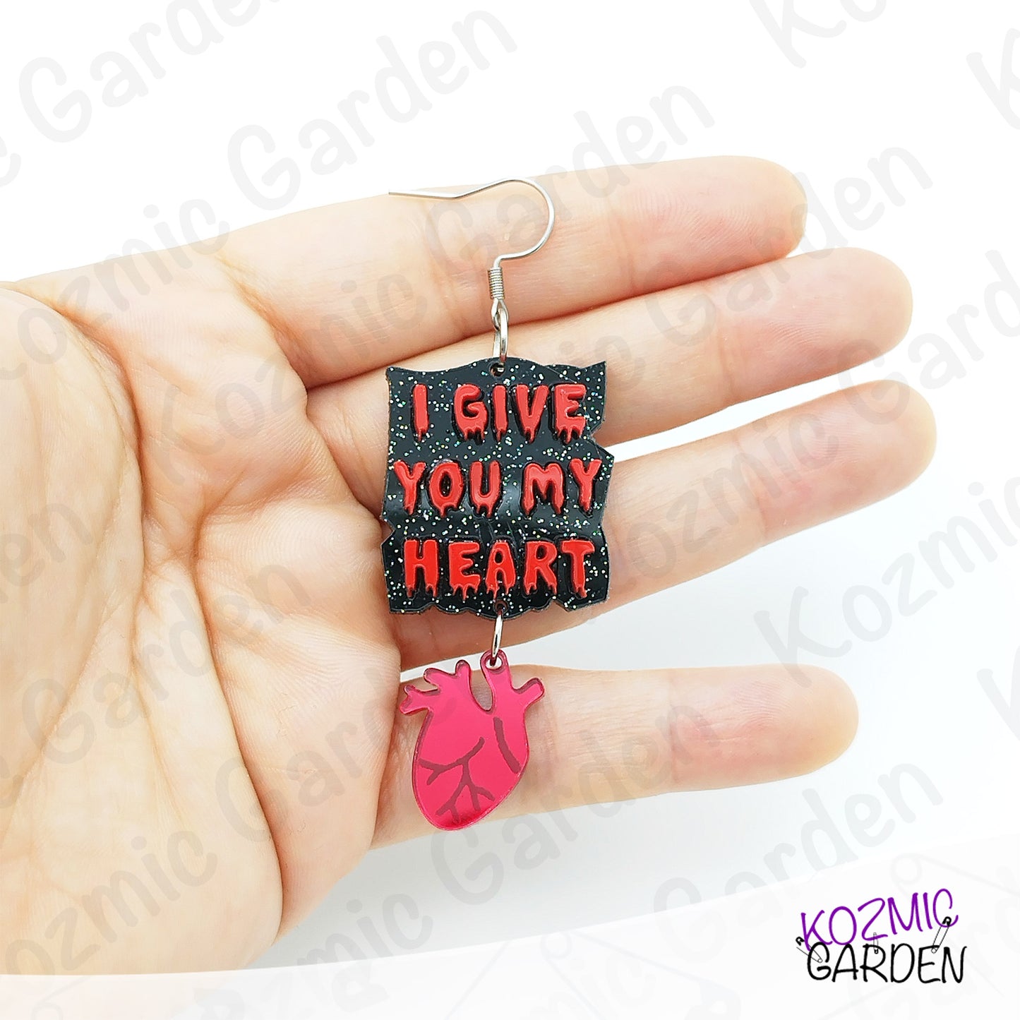 Earring with 'I Give You My Heart' text and anatomical heart design held in a hand.
