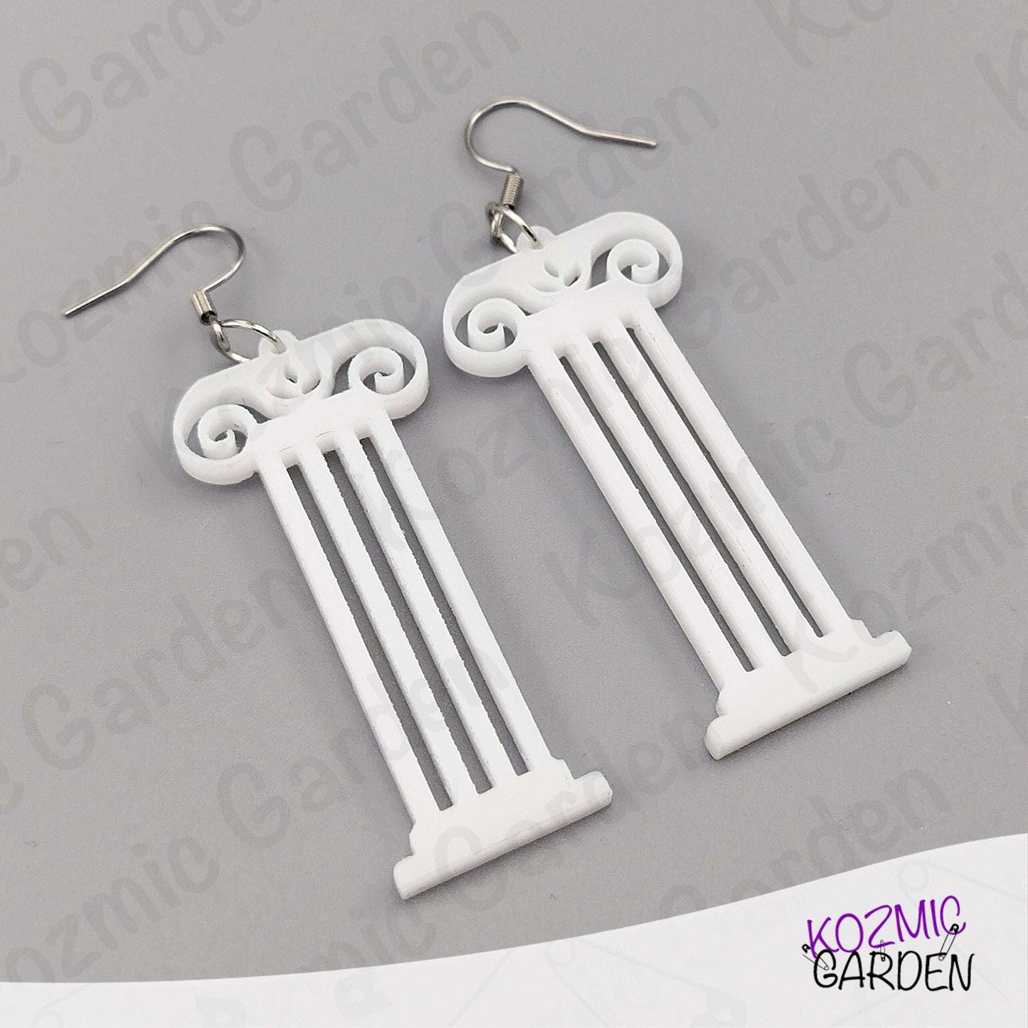 White column-shaped earrings on a gray background with 'Kozmic Garden' branding.