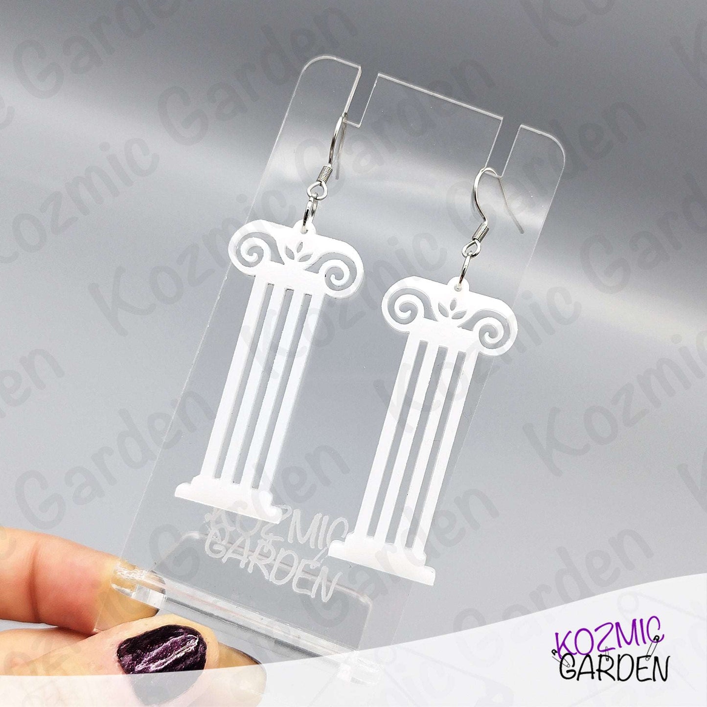 White column-shaped earrings on a clear Kozmic Garden display card.