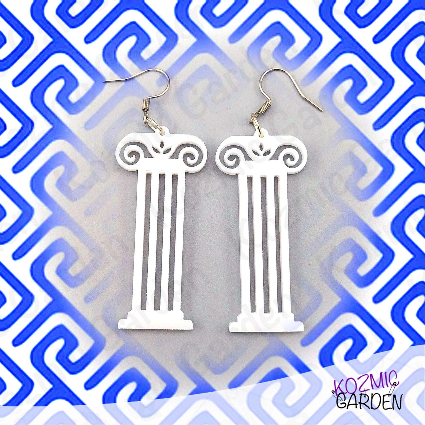White column-shaped earrings on a blue and white geometric patterned background with 'Kozmic Garden' branding.