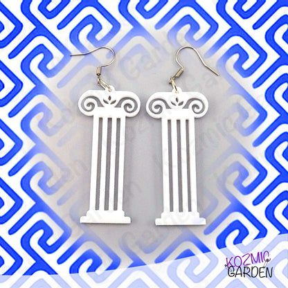 White column-shaped earrings on a blue and white geometric patterned background with 'Kozmic Garden' branding.