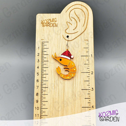 Wooden ruler with a shrimp ornament wearing a Santa hat on a gray background, branded 'Kozmic Garden'.