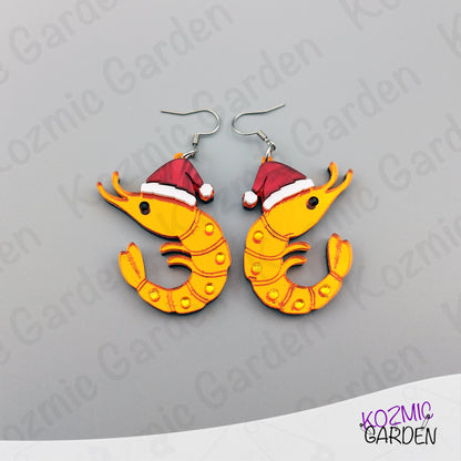 Shrimp earrings with Santa hats on a gray background, branded 'Kozmic Garden'.