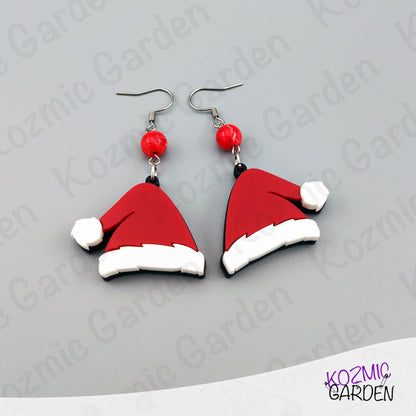 Santa hat earrings with red beads on a gray background, branded 'Kozmic Garden'.